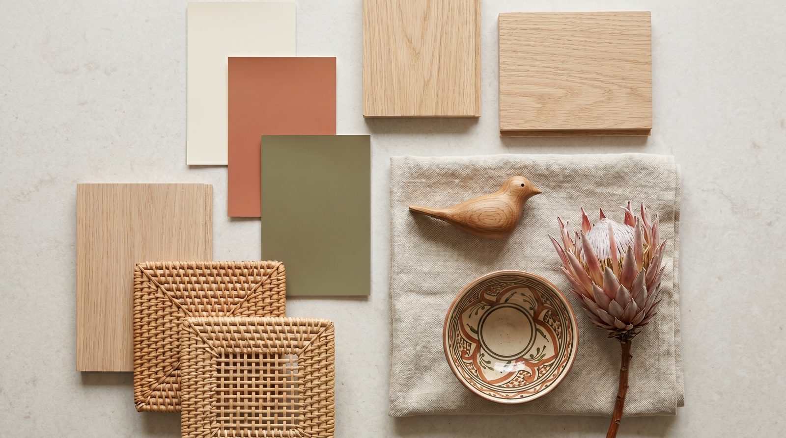 An interior styling mood board with warm-neutral paint swatches, light oak and rattan textures, linen fabric and South African décor accents